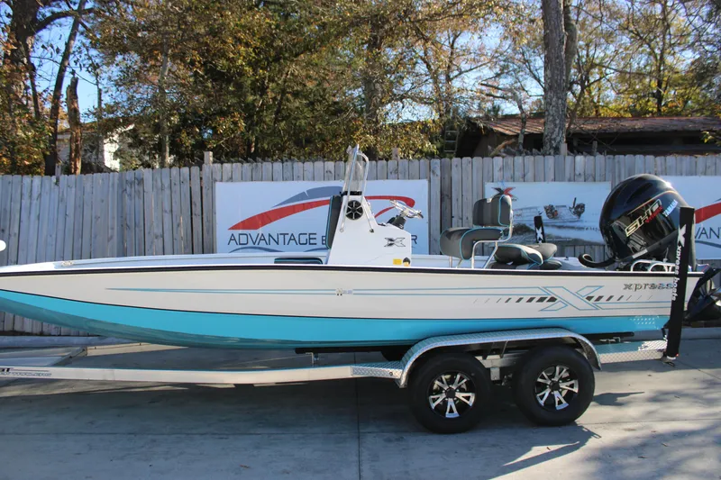 The Image of 2026 Xpress H22B Bay boat on trailer, displayed outdoors with trees and fence background. - 1