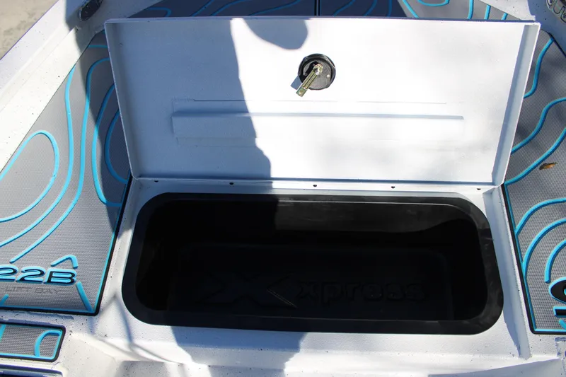 Slide: The Image of 2026 Xpress H22B Bay boat storage compartment with open lid and key lock. - 24