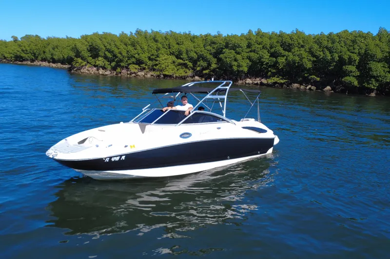 Slide: The Image of 2006 Monterey 263 Explorer Sport boat cruising on a serene lake with lush green shoreline. - 10