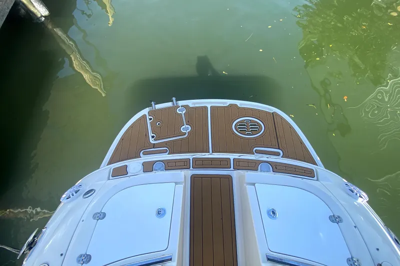 Slide: The Image of 2006 Monterey 263 Explorer Sport boat deck, featuring wood accents and water reflection. - 12