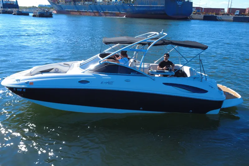 Slide: The Image of 2006 Monterey 263 Explorer Sport boat on water, with passengers, near a large ship. - 4