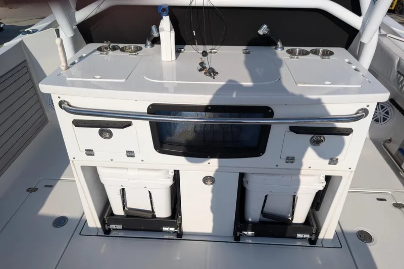 Slide: The Image of 2024 Blackfin 332 CC boat console with storage compartments and fishing equipment. - 19