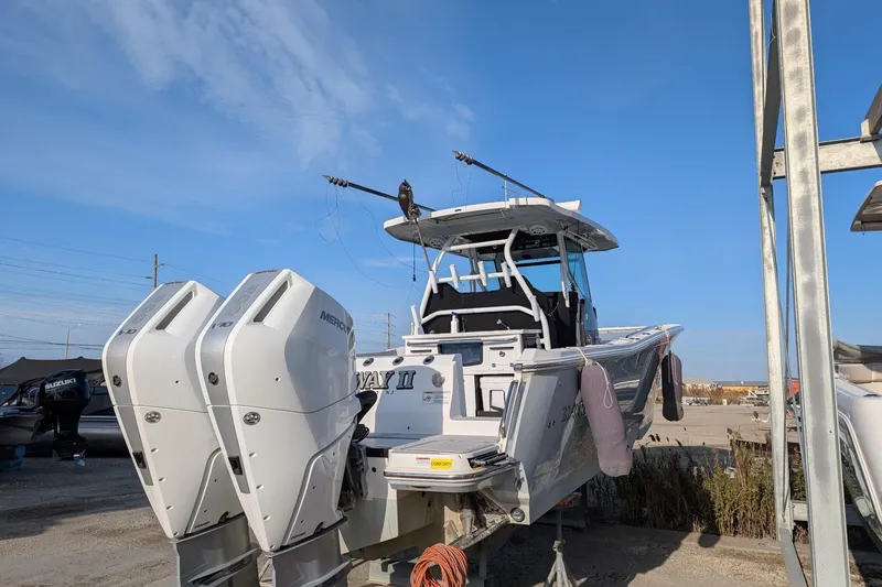 Slide: The Image of 2024 Blackfin 332 CC boat with dual Mercury outboard engines, docked under clear blue sky. - 2