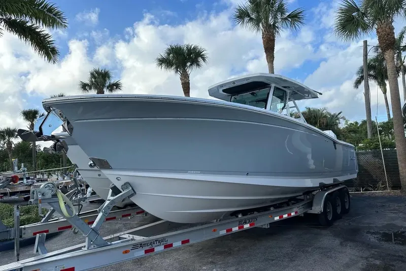Slide: The Image of 2024 Blackfin 332 CC boat on trailer, surrounded by palm trees under a blue sky. - 23