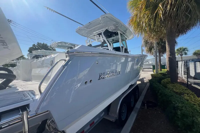Slide: The Image of 2024 Blackfin 332 CC boat parked under palm trees on a sunny day. - 25