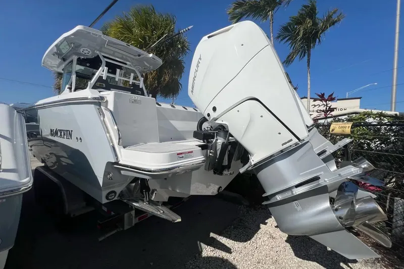 Slide: The Image of 2024 Blackfin 332 CC boat with powerful Mercury outboard engine, parked under palm trees. - 27