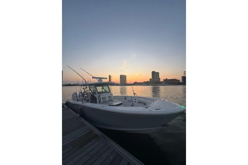 Slide: The Image of 2024 Blackfin 332 CC boat docked at sunset with city skyline backdrop. - 5