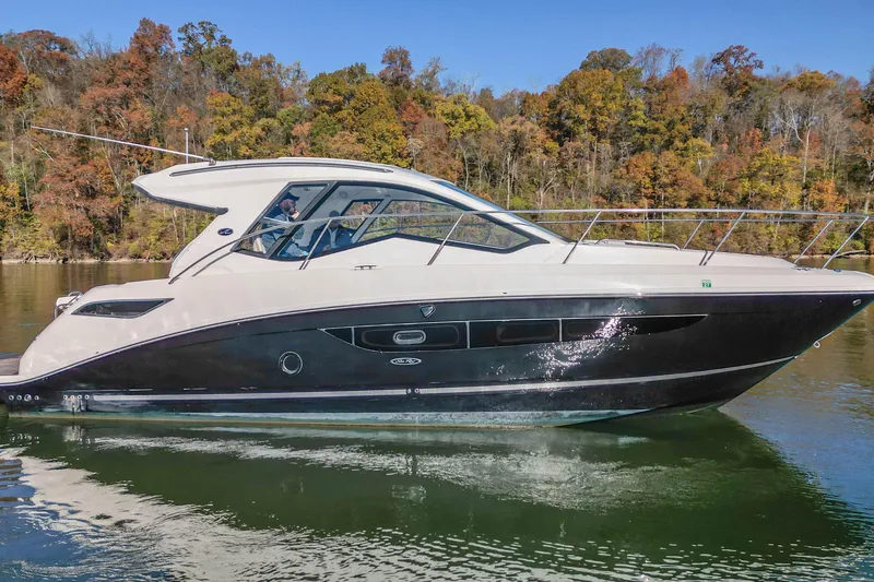 Slide: The Image of 2018 Sea Ray Sundancer 350 Coupe cruising on a calm lake with autumn foliage backdrop. - 1