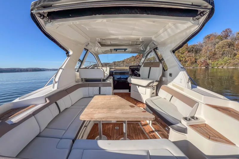 Slide: The Image of 2018 Sea Ray Sundancer 350 Coupe interior with seating and table on a calm lake. - 20
