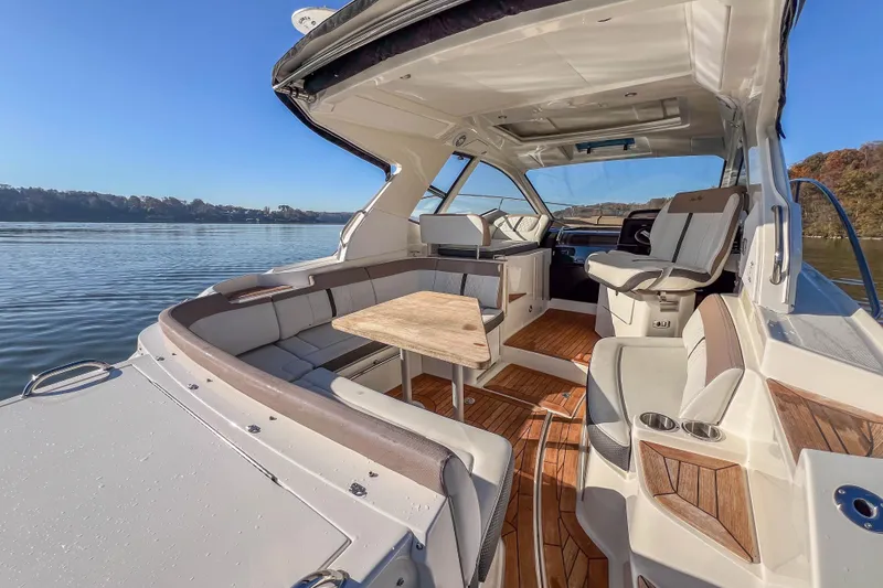 Slide: The Image of 2018 Sea Ray Sundancer 350 Coupe interior with seating and table on calm water. - 23