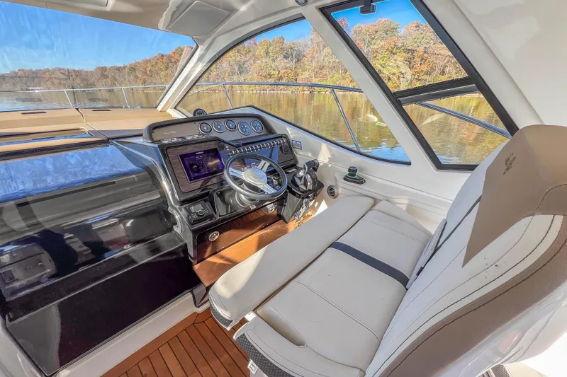 Slide: The Image of 2018 Sea Ray Sundancer 350 Coupe helm with modern controls and scenic lake view. - 24