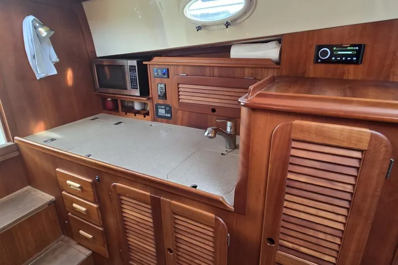 Slide: The Image of 2009 Hinckley 37 yacht interior kitchen with wooden cabinetry and modern appliances. - 26