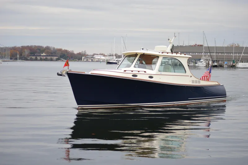 Slide: The Image of 2009 Hinckley 37 boat on calm water, with flags, near a marina. - 3