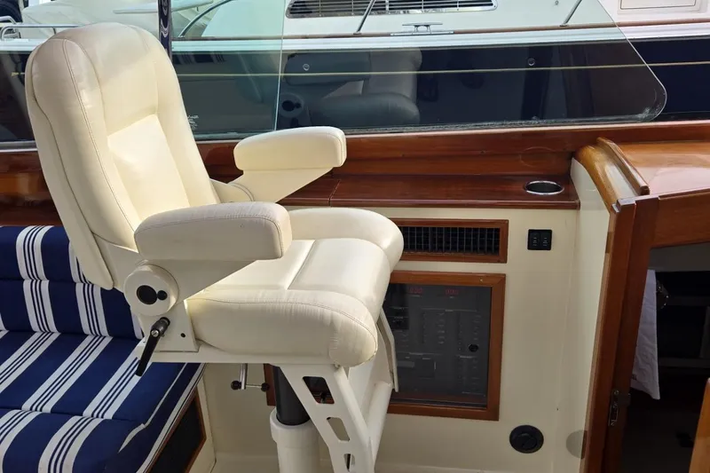 Slide: The Image of Luxury seating on a 2009 Hinckley 37 yacht, featuring a white captain's chair and striped cushions. - 21
