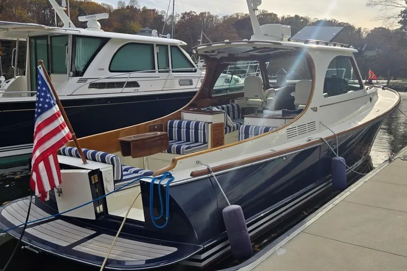 Slide: The Image of 2009 Hinckley 37 yacht docked, featuring striped seating and an American flag. - 8