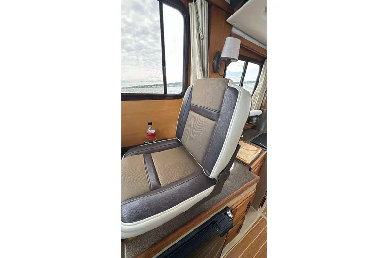 Slide: The Image of Interior of 2014 Ranger Tugs R-27 boat with cushioned seating and window view. - 16