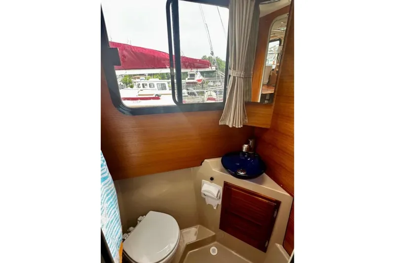 Slide: The Image of 2014 Ranger Tugs R-27 boat bathroom with window, sink, and toilet. - 19