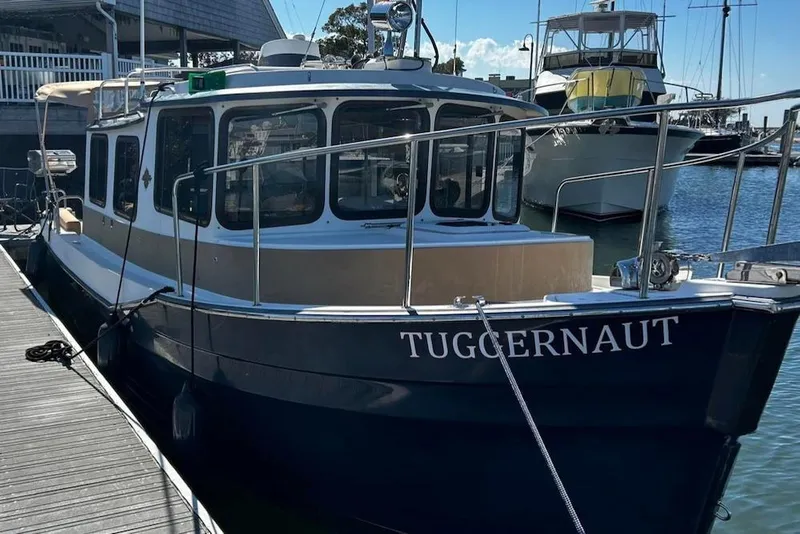 Slide: The Image of 2014 Ranger Tugs R-27 boat named "Tuggernaut" docked at a marina. - 2