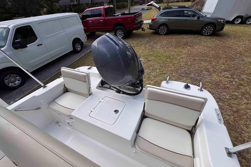 Slide: The Image of 2017 NauticStar 1810 NauticBay boat with seating and motor, parked near vehicles. - 16
