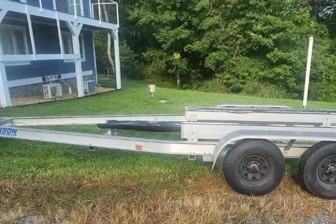 Slide: The Image of Trailer for 2009 Scout 240 Bay Scout boat parked on grass near a house. - 27