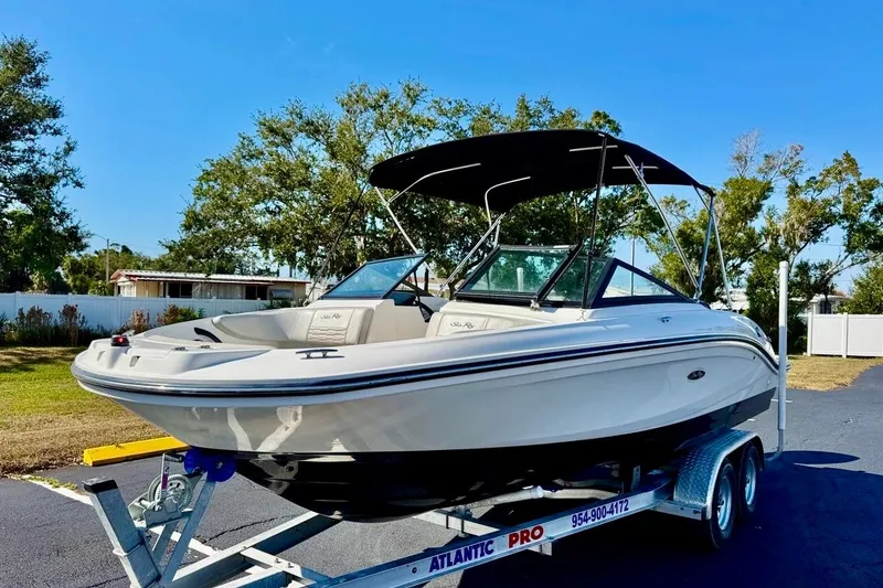 Slide: The Image of 2023 Sea Ray SPX 210 Outboard boat on trailer, parked outdoors under clear blue sky. - 2