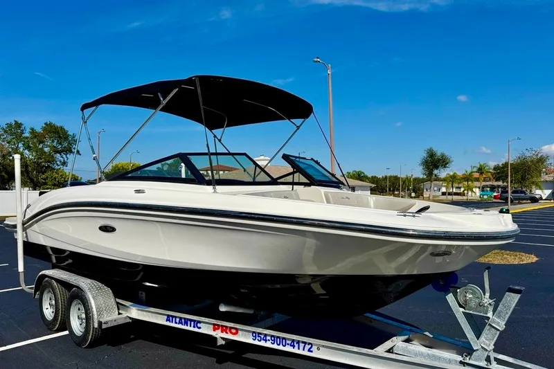 Slide: The Image of 2023 Sea Ray SPX 210 Outboard boat on trailer, parked outdoors under clear blue sky. - 4
