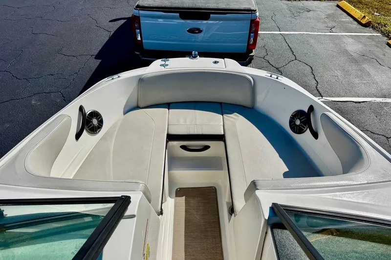 Slide: The Image of 2023 Sea Ray SPX 210 Outboard boat interior with seating and speakers, parked near a truck. - 9