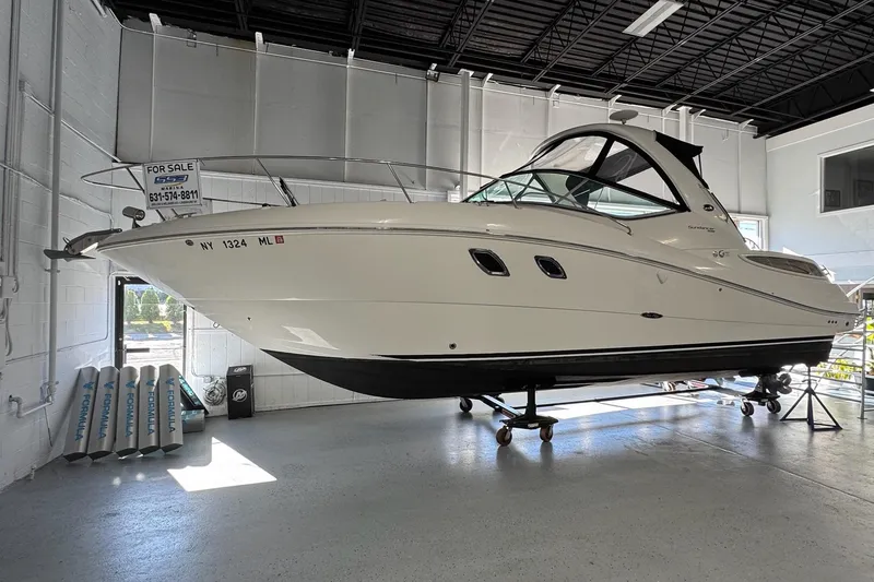 Slide: The Image of 2014 Searay 330 Sundancer boat displayed indoors on a stand. - 2