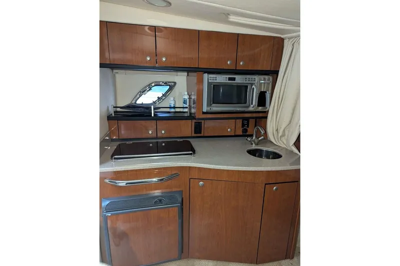 Slide: The Image of 2007 Sea Ray 310 Sundancer galley with microwave, sink, and wooden cabinetry. - 12