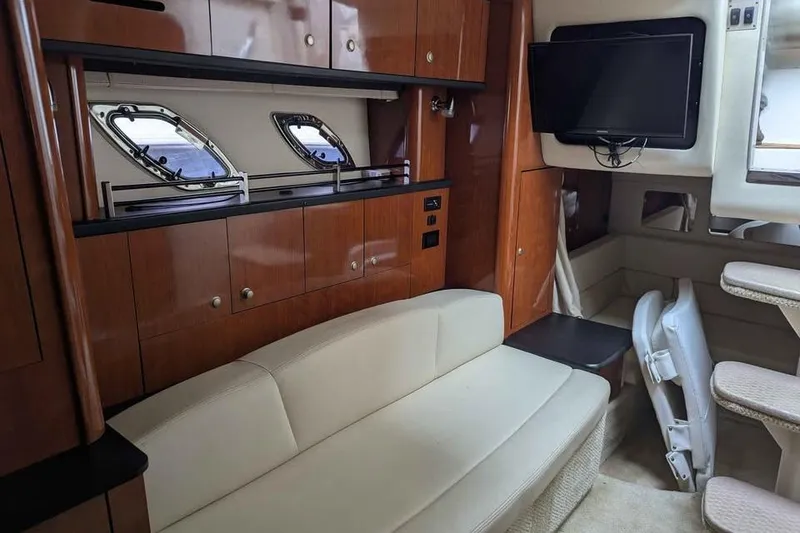 Slide: The Image of Interior of 2007 Sea Ray 310 Sundancer with beige seating, wood cabinets, and mounted TV. - 14