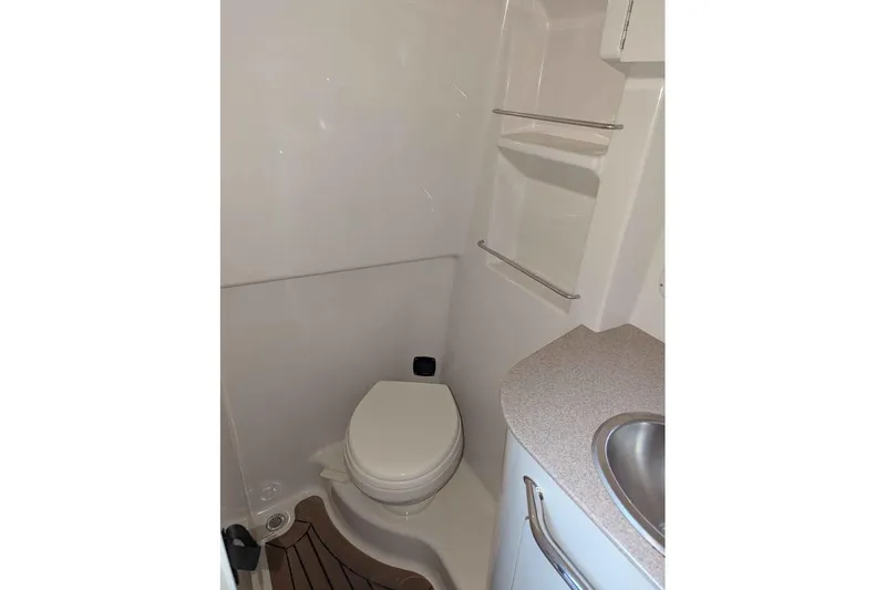 Slide: The Image of 2007 Sea Ray 310 Sundancer bathroom with toilet, sink, and storage shelves. - 17