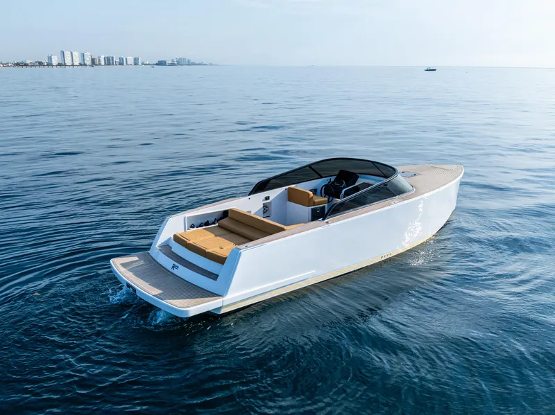 Slide: The Image of 2023 VanDutch 32 yacht cruising on calm ocean waters, city skyline in background. - 2