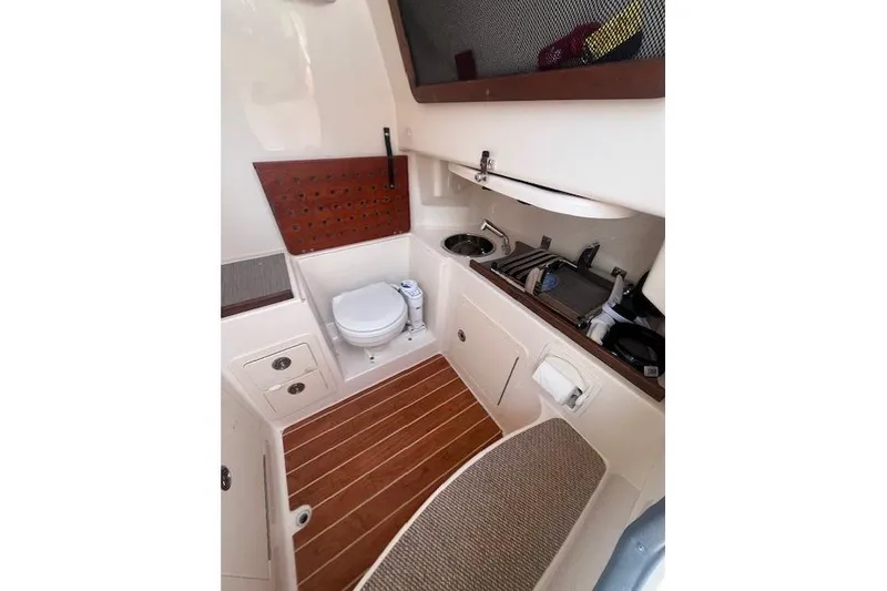 Slide: The Image of 2023 Grady-White Canyon 306 boat interior with toilet, sink, and wooden flooring. - 25