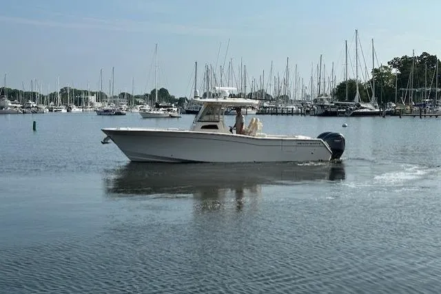 Slide: The Image of 2023 Grady-White Canyon 306 boat cruising in a marina with sailboats in the background. - 3