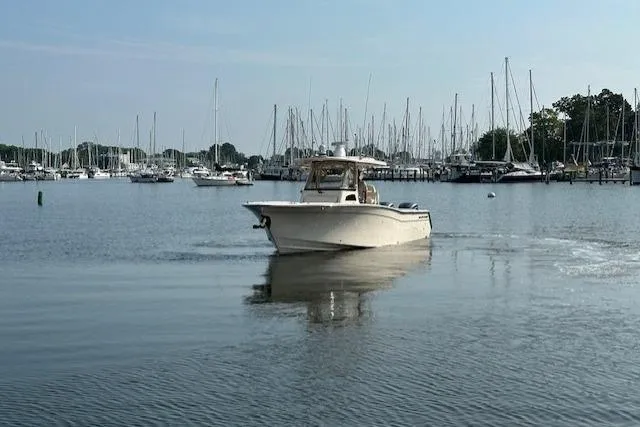 Slide: The Image of 2023 Grady-White Canyon 306 boat cruising in a marina with sailboats in the background. - 4