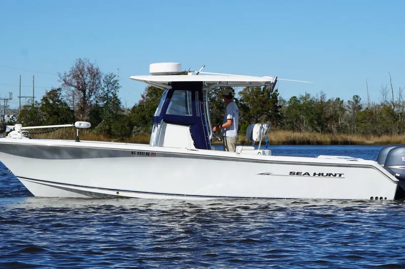 Slide: The Image of 2011 Sea Hunt Gamefish 25 boat cruising on a calm lake with trees in the background. - 3