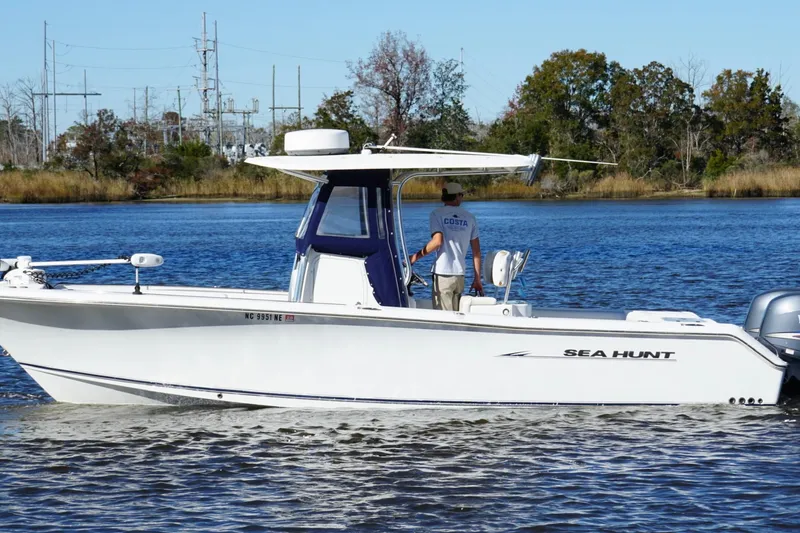 Slide: The Image of 2011 Sea Hunt Gamefish 25 boat cruising on a calm lake with trees in the background. - 5