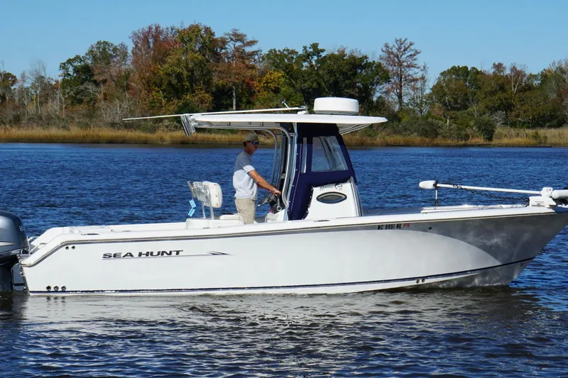 Slide: The Image of 2011 Sea Hunt Gamefish 25 boat on calm water with trees in the background. - 6