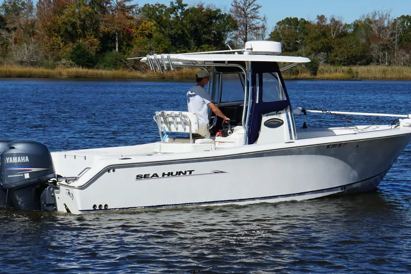 Slide: The Image of 2011 Sea Hunt Gamefish 25 boat on water with Yamaha engine, surrounded by trees. - 7