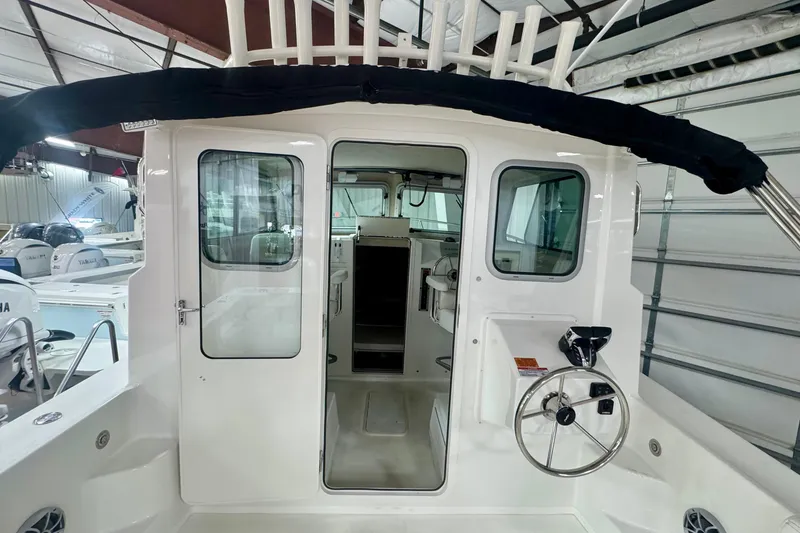 Slide: The Image of 2026 Parker 2520 XLD Sport Cabin boat interior with steering wheel and cabin entrance. - 8