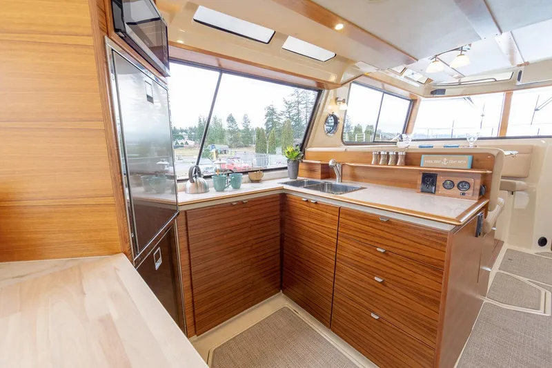 Slide: The Image of Manufacturer Provided Image: Luxurious 2025 Ranger Tugs R-43 CB yacht kitchen with modern wood cabinetry and large windows. - 9