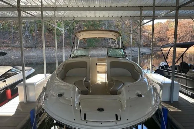 Slide: The Image of 2002 Sea Ray 240 Sundeck boat docked under a covered marina with autumn trees in the background. - 10