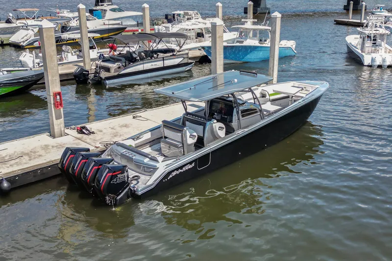 Slide: The Image of 2021 Nor-Tech 390 Sport Center Console boat docked at marina with multiple engines. - 2