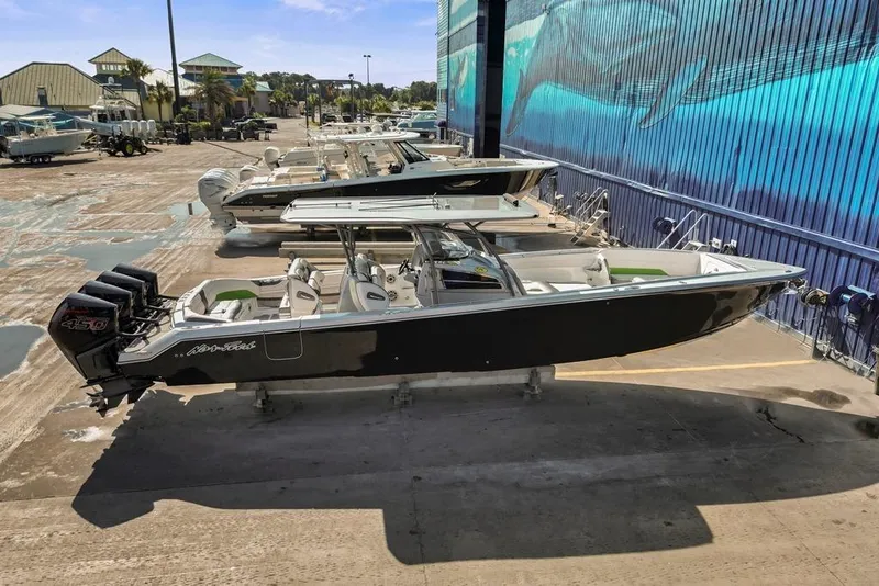 Slide: The Image of 2021 Nor-Tech 390 Sport Center Console boat with triple outboard engines in a marina setting. - 38