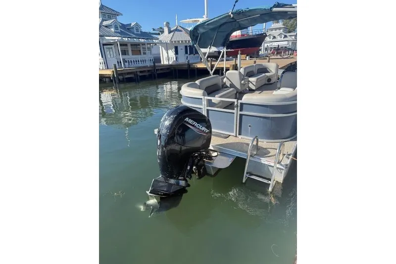 Slide: The Image of 2024 Island Breeze 232 pontoon boat with Mercury outboard motor docked at marina. - 3