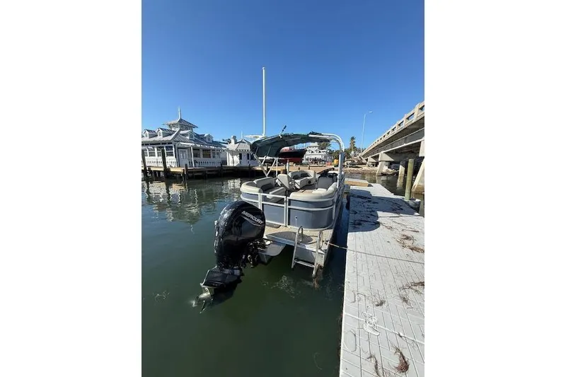 Slide: The Image of 2024 Island Breeze 232 pontoon boat docked by a marina under clear blue skies. - 5