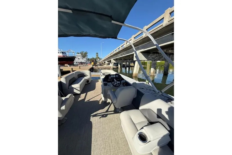 Slide: The Image of 2024 Island Breeze 232 boat interior with seating, under a bridge on a sunny day. - 7