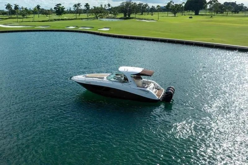 Slide: The Image of 2010 Sea Ray 370 Sundancer yacht on a serene lake near a golf course. - 8
