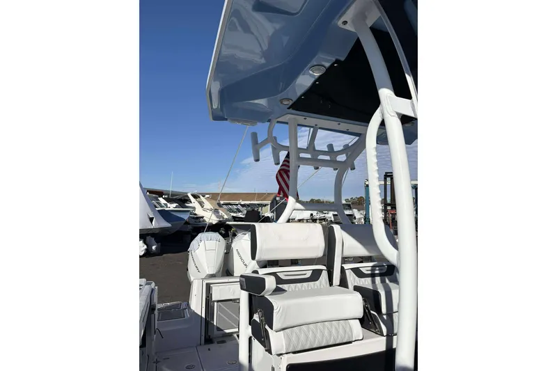Slide: The Image of 2024 Blackfin 302CC boat interior with seating and rod holders, docked under clear sky. - 11