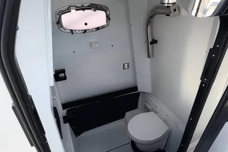 Slide: The Image of 2024 Blackfin 302CC boat interior with compact marine toilet and window. - 14
